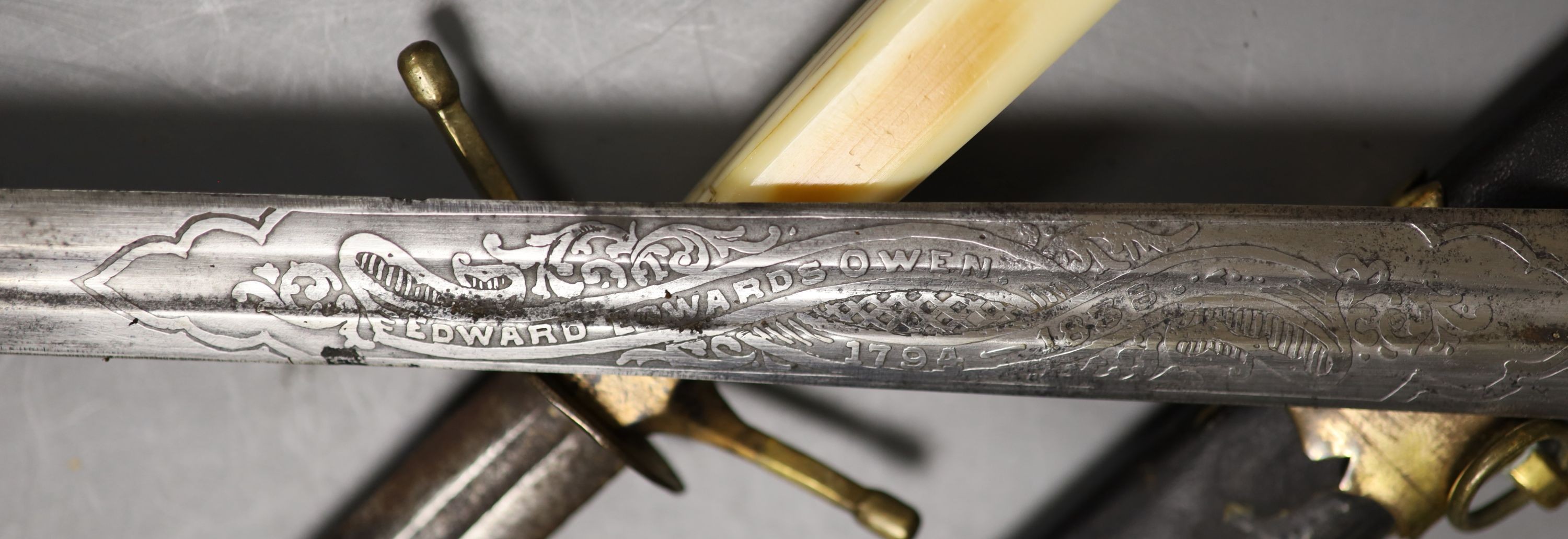 A Georgian naval dirk 41 cm flattened diamond blade etched EDWARD EDWARDS OWEN 1794-1838., Grip with engraved central copper band with traces of a rampart lion. Contained in its copper gilt mounted leather scabbard. Toge